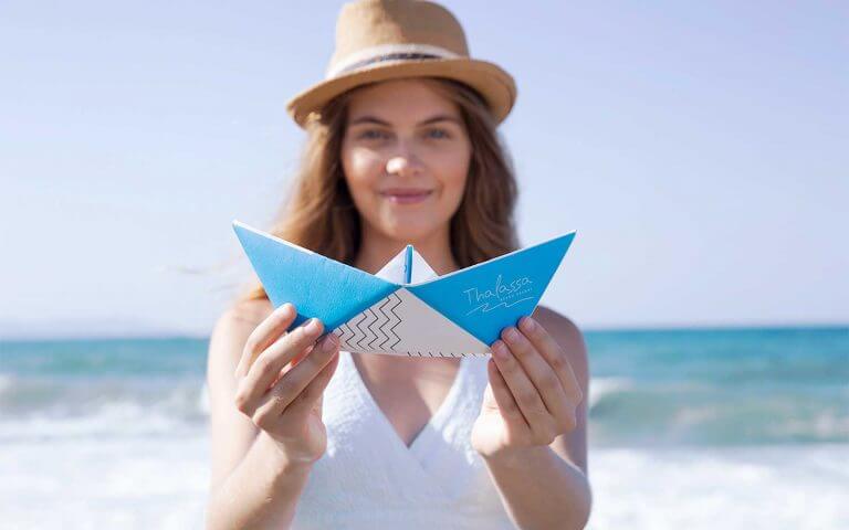 Woman holding origami ship with thalassa logo