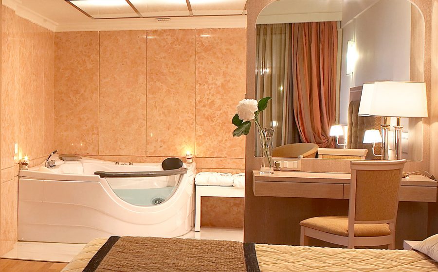 Bath, bed and table with chair and mirror of a superior suite