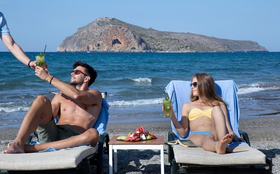 Couple on sunbeds having drinks served