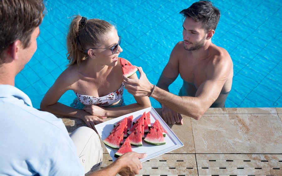 Couple in pool having watermelon served