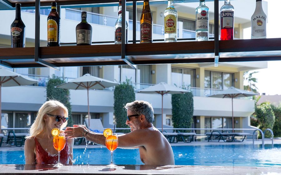 Playfull couple having drinks at the pool bar