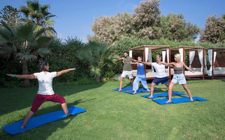 Two couples taking yoga class from instructor outdoors