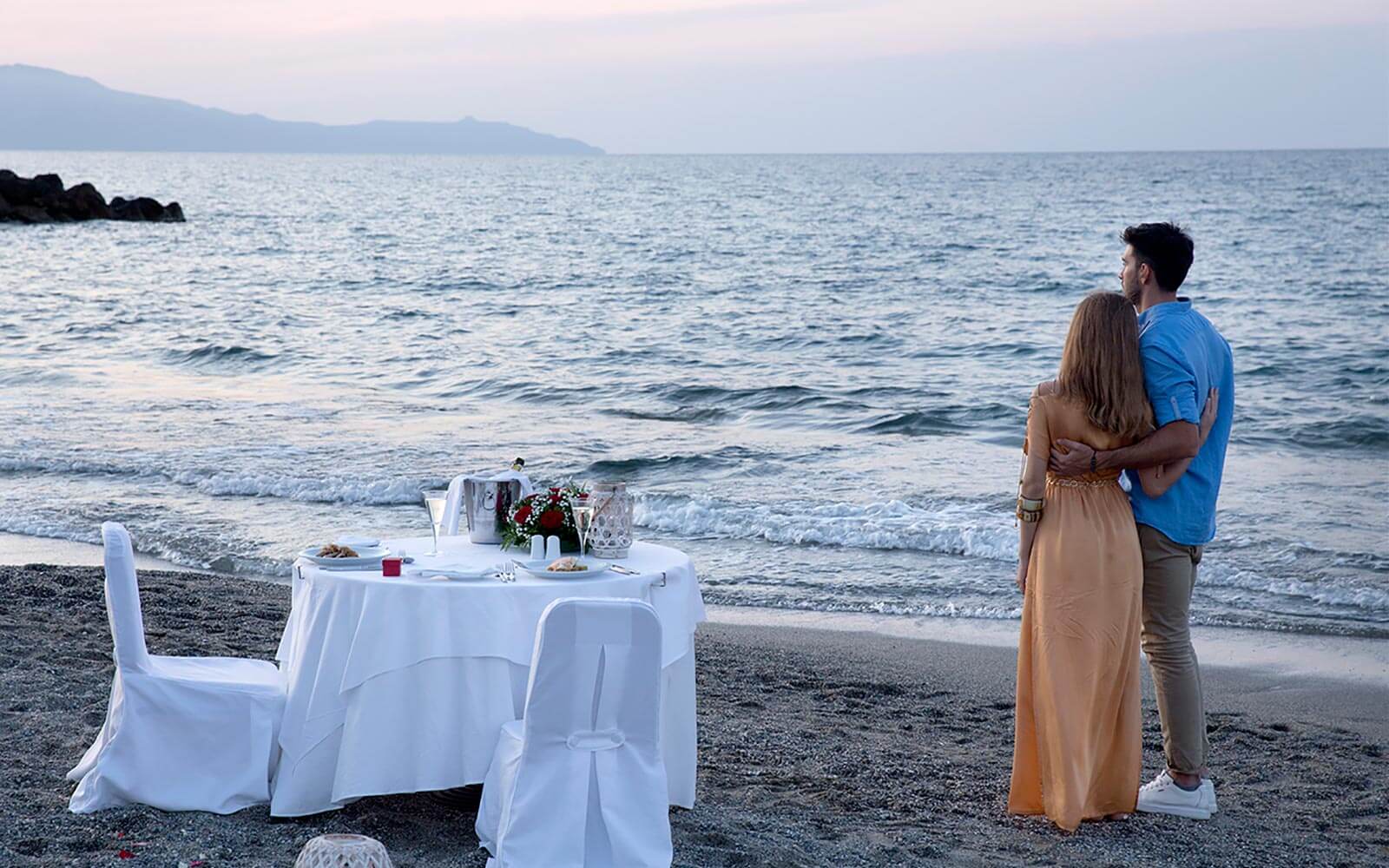 Couple watching the sunset near a table by the sea